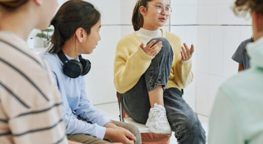 A teenage girl talks in a circle of other young people