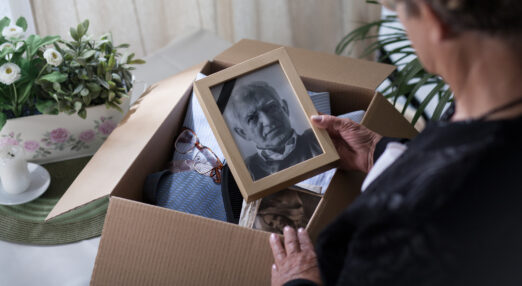 A woman looks at a framed picture of an older man taken from a box of keepsakes